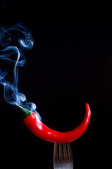 smoking chili pepper on fork on black background - 135572968