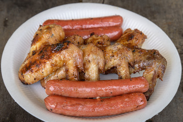 Grilled marinated chicken sausages and wings on white polystyren