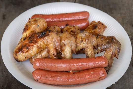 Grilled marinated chicken sausages and wings on white polystyren