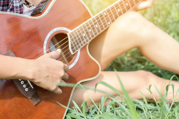 Fototapeta premium Young hipster girl sitting playing a guitar and singing.