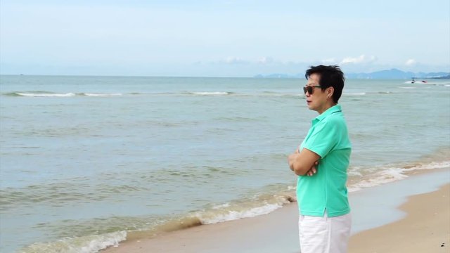 Asian senior woman wearing sunglasses and thinking about life planning next to the sea