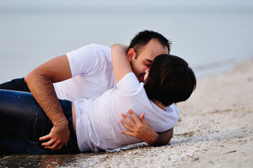 Happy in the arms of a young couple lying on the sand beach