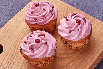 Tasty cupcakes on wooden board.