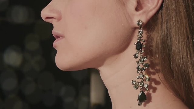 Beautiful girl in a beautiful earrings with shiny stones in the profile of the sun with blurred background, HD