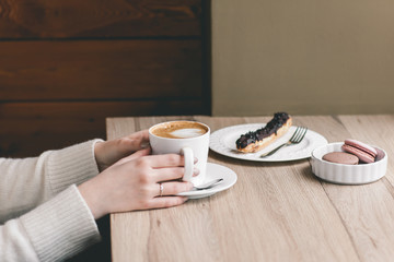 Womans hands wrapped around a cup on wood table with chocolate e