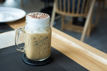 A glass of ice cappuccino art with foods on table