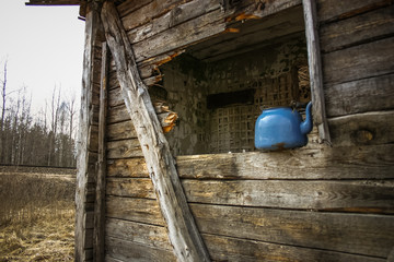 An old, rusty tea pot in ruins of old house in early spring