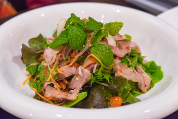 Asian spicy sliced pork steak salad in white plate. shallow focu
