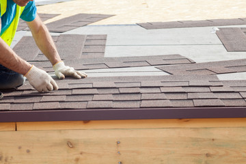 Roofer builder worker installing roof shingles © brizmaker