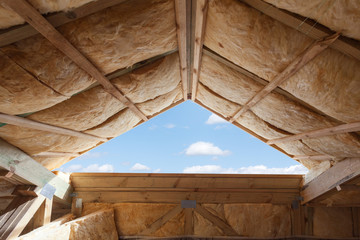 Fibreglass insulation installed in the sloping ceiling of a new frame house. - obrazy, fototapety, plakaty