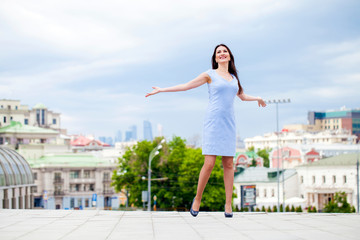 Young beautiful woman in a blue dress walking on the summer stre
