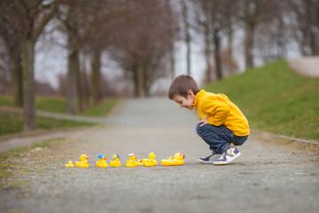 Adorable child, boy, playing in park with rubber ducks, having f
