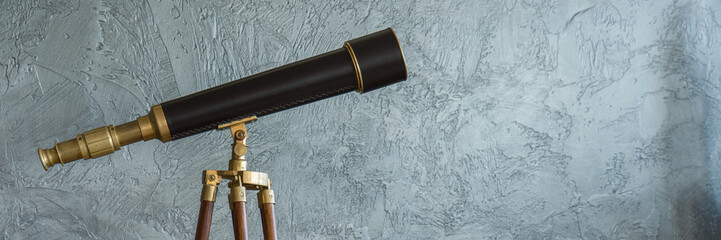 Antique telescope and grey wall