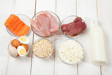 Proteins, fish, cheese, eggs, meat and chicken on a white wooden background