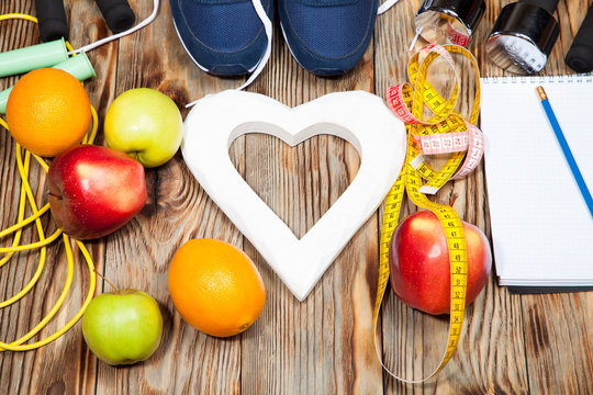 Heart, apples and oranges, diet, healthy , dumbbells  a jump rope on  wooden background