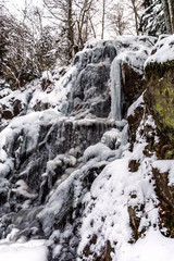 Fototapeta na wymiar Beautiful icy waterfall in the forest. Vosges mountains.