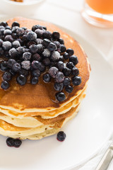 Stack of pancakes with frozen blueberries and honey on white wooden table. Selective focus