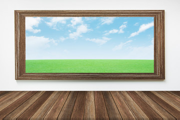 picture frame green grass and sky on the wall and the table wood