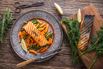 Salmon fillets. Grilled salmon, sesame seeds herb decoration on vintage pan or black slate board. fish roasted on an old wooden table.Studio shot.