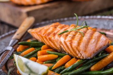 Salmon fillets. Grilled salmon, sesame seeds herb decoration on vintage pan or black slate board. fish roasted on an old wooden table.Studio shot.
