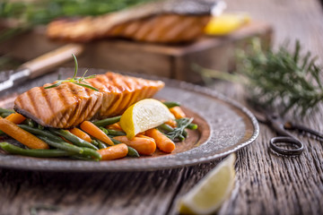 Salmon fillets. Grilled salmon, sesame seeds herb decoration on vintage pan or black slate board. fish roasted on an old wooden table.Studio shot.