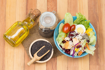 Fresh salad with fruits and Black sesame seeds and oil  on woode