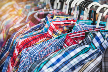 close up cloth hangers with men shirts on rail in clothing store 