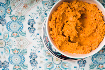 Hummus in the ceramic bowl on the background with patterns horizontal