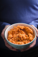 Bowl with hummus on the hands vertical