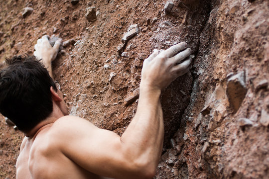 Male Rock Climber Ascending Cliff Face, Chalked Hands, Back View