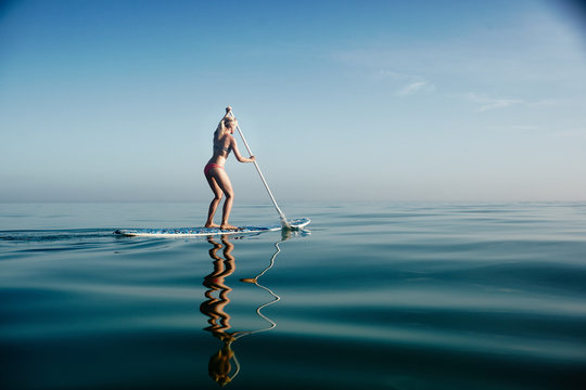 Female paddle boarding on calm water 