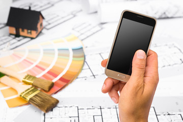 Male Hand holding a Smart Phone over Construction plans