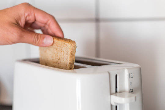 Putting a slice of bread to the toaster