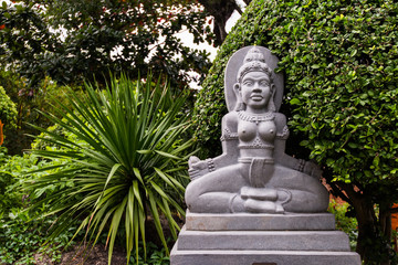 Statue of Buddha on stone platform in temple surrounded by green trees