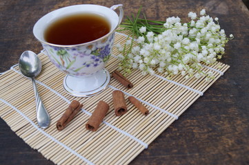 Bouquet of flowers and cup of tea on a wooden table
