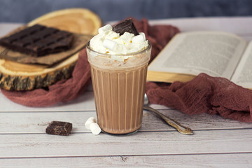 Hot chocolate or cocoa in glass with whipped cream and pieces chocolate