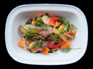 Roast beef and vegetables in enamel plate isolated on black