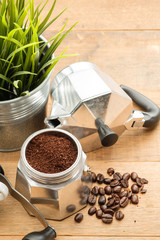 Coffee grounds in moka pot and coffee beans on wood table close