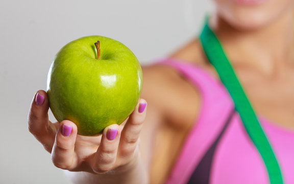 woman fit girl with measure tape and apple fruit