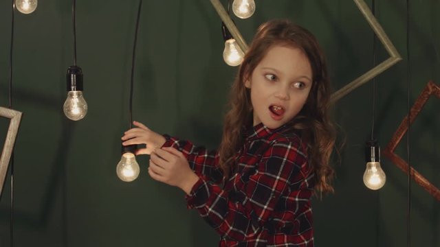 Little girl posing with light bulbs that hang on wires