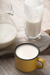 Glass and pitcher of kefir and cup on a white stand