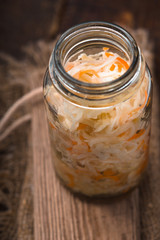 Sauerkraut in a glass jar on a wooden table