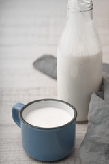 Cup with kefir, a bottle and napkin on a wooden table