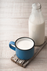 Blue cup with kefir and a bottle on a wooden stand