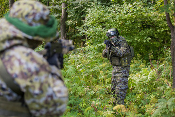 Military man in camouflage with guns in the woods