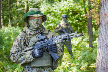 Military man in camouflage with guns in the woods