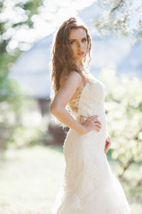 Bride looks seductive posing in green park in rays of bright sun