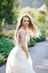 Bride in long lace dress shakes her hair while she walks along t