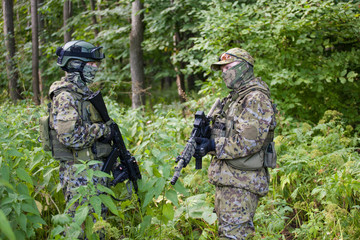 Military man in camouflage with guns in the woods