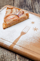 A piece of sliced apple pie with cinnamon on vintage wooden background texture.